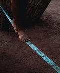 Close-up of feet balancing on a 60 Feet Slackline Kit With Tree Guards, Carry Bag, And Easy Setup For Family Fun, Kids And Adults