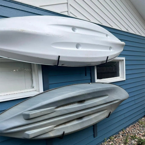 Top Shelf Badass Kayak Wall Mount Rack For Garage Storage with three kayaks securely hung on a blue wall.