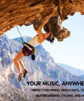 Woman rock climbing with Compact Waterproof Portable Bluetooth Speaker That Goes Hard With Deep Bass attached to harness.