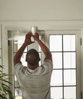 Man installing Winter Window Insulation Kit With Roll Shrink Film That Covers Up To 15 Windows Measuring 3 By 5 Feet Tape Included.