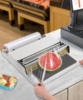 Rock Solid No Sweat Hand Cling Wrap Sealer And 18 Inch Food Packaging Machine used to seal a sliced watermelon in a commercial kitchen.