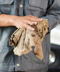 Person holding recycled multipurpose industrial wiping cloths 49 lb pack assorted colors eco friendly cleaning rags for grease and oil cleanup