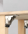 Heavy duty folding table leg brackets on wooden desk, showing silver steel construction with self-locking mechanism at 0 and 90 degrees.
