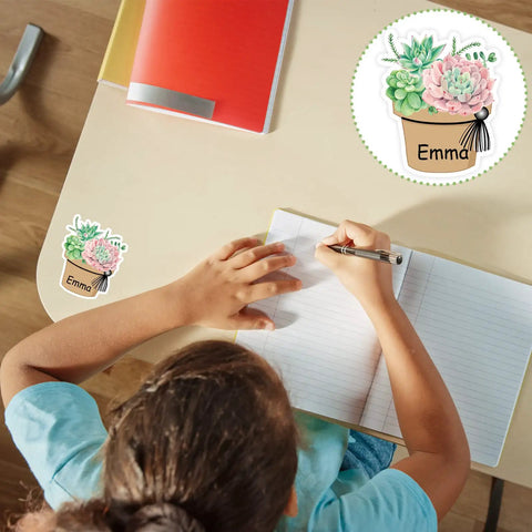 Child writing near succulent name tag sticker reading 'Emma' from 120 Pieces Dope Succulent Name Tag Stickers Set With 12 Designs.