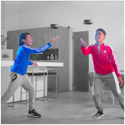 Two kids playing indoors with Gravitor Hand Controlled Flying Toy With Trick Stick USB Rechargeable Drone For Kids 4 And Up Wave Control Hover Toy That Senses Altitude No Remote Needed