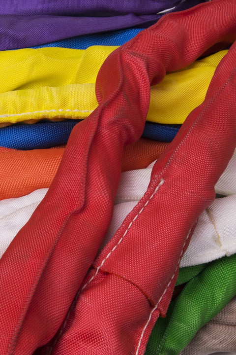 Multiple industrial slings in various colors, including red, yellow, and purple, stacked; Endless Purple Polyester Round Sling visible