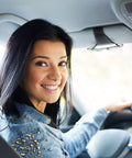Smiling woman driving a car with a Heavy Duty Magnetic Sunglass Holder For Car Sun Visor With Secure Snap Clip and Soft Leather Wrap.
