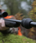 Close-up of black vibration dampening barrel device for standard barrels made of NAVCOM material in outdoor setting.