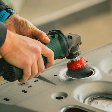 Green angle grinder with red grinding wheel, close-up view on metal surface.