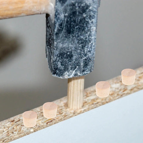 Hammer securing tapered wood plugs for screw holes with button plug head in furniture, lightweight repair caps for DIY projects.