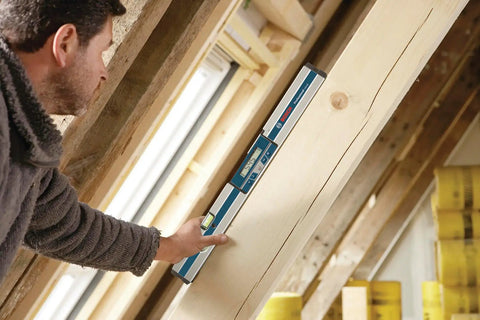 Person using GIM 60 24 Inch Digital Level with Illuminated Rotating Display on wooden beam at construction site