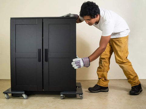 Man using Heavy Duty Low Profile Desk Cabinet Corner Mover Dolly Set Of 4 Premium Quiet Pu Rollers With 1320 Lb Capacity to move black cabinet.