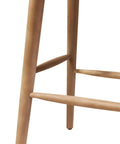 Close-up of leg detail on Magwen Outdoor Acacia Wood Barstool With Wicker Set Of Two Rustic Patio Seating, light brown wood.