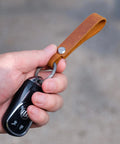 Hand holding Top Shelf Crazy Horse Leather EDC Keychain Strap With Aerospace Titanium Key Ring For Car Keys.