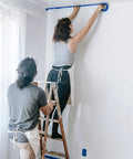 Person applying Blue Multi-Surface Painter's Tape 0.94 In X 60 Yds, 6 Rolls, Residue Free Masking Tape for pro DIY finish lines on wall.