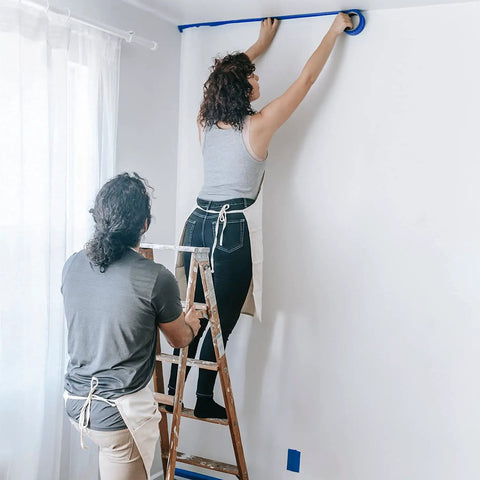 Person applying Blue Multi-Surface Painter's Tape 0.94 In X 60 Yds, 6 Rolls, Residue Free Masking Tape for pro DIY finish lines on wall.
