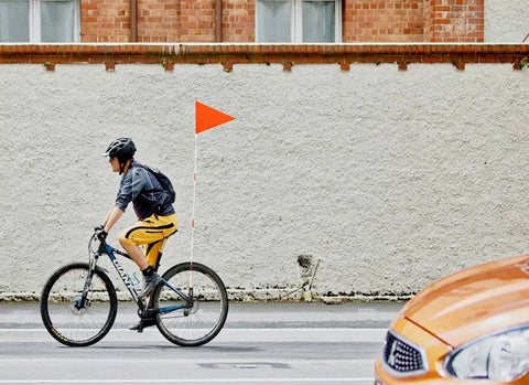 Cyclist with Two Pack Upgraded Bike Flags With Poles For Maximum Road Visibility, 6 Ft High Visibility Orange Flag on city street