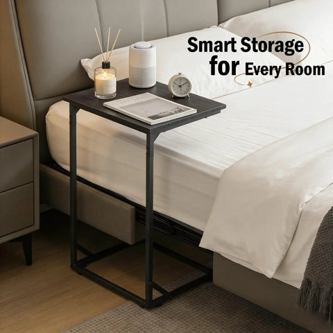 C Shaped End Table That Slides Under Sofa For Small Spaces beside bed with clock and candle on top, black steel frame