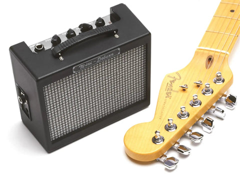 MD 20 Mini Deluxe Guitar Amp Bundle With Power Supply, Instrument Cable, Picks and Road Ready Portable Practice Amp next to guitar neck
