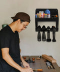 Man working in a workshop with a wall mount power tool organizer five drill holder rack heavy duty cordless drill storage rack in view.