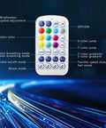 Remote control for Mini 6W Starlight Headliner Kit with buttons for color and twinkle settings visible, fiber optic lights in background