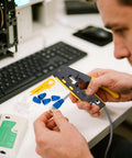 Person using Pro Grade RJ45 Crimp Tool Pass Through Kit with Built-In Tester focusing on Cat6 connectors near keyboard setup.