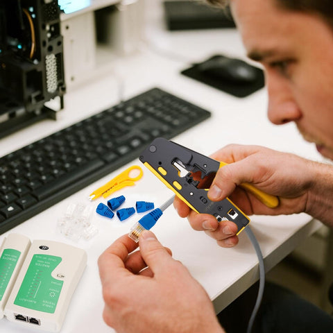 Person using Pro Grade RJ45 Crimp Tool Pass Through Kit with Built-In Tester focusing on Cat6 connectors near keyboard setup.
