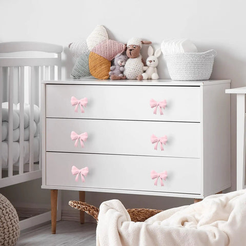 White dresser with Pink Bow Dresser Knob Set With 30 Knobs And 90 Screws, 1.57 Inch Aluminum Alloy Handles adorning drawers.