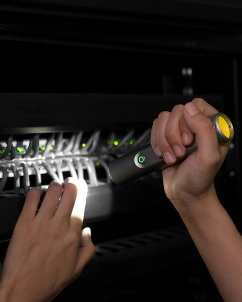 Person using Tiny But Mighty LED Flashlight Rechargeable USB C in server room, illuminating cables. Compact design, durable material.