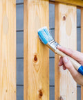 Hand painting wooden fence with blue brush, showcasing use of 200 Pack Solid Wood Pocket Hole Plugs For Woodworking Jig Pine Plugs For Three Eighths Inch Holes Durable Pocket Screw Plug Set Pro Grade Woodworking Gear You Can Trust.