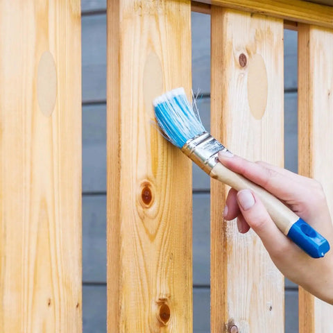 Hand painting wooden fence with blue brush, showcasing use of 200 Pack Solid Wood Pocket Hole Plugs For Woodworking Jig Pine Plugs For Three Eighths Inch Holes Durable Pocket Screw Plug Set Pro Grade Woodworking Gear You Can Trust.
