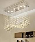Modern Wave Rectangular Crystal Raindrop Chandelier With Chrome Finish Flush Mount Pendant Lighting, illuminating a dining room.