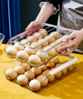 Two Layer Ramp Type Auto Rolling Egg Holder For Fridge Organizer Large Clear Egg Bin Stackable Egg Storage Tray With Front Load Roll Forward Design For Easy Access Daily Use, stacked and filled with eggs on a table.