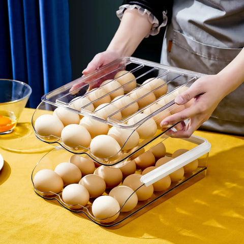 Two Layer Ramp Type Auto Rolling Egg Holder For Fridge Organizer Large Clear Egg Bin Stackable Egg Storage Tray With Front Load Roll Forward Design For Easy Access Daily Use, stacked and filled with eggs on a table.