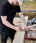Machinist square being used to mark a wooden board on a workbench.