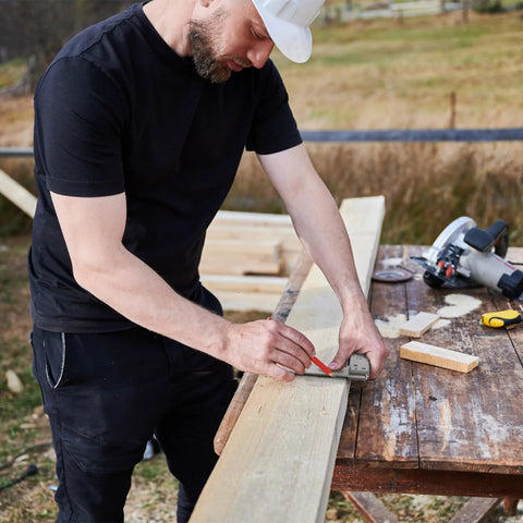 Machinist square being used to mark a wooden board on a workbench.
