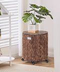Round Water Hyacinth Storage Basket With Lid And Wheels boho chic, in a living room, with a plant on top, rattan bin with metal frame.