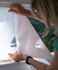 Person installing Privacy Frost Window Film 26 By 59 Inch Roll Reusable Static Cling Removable Decorative Glass Cover on window.