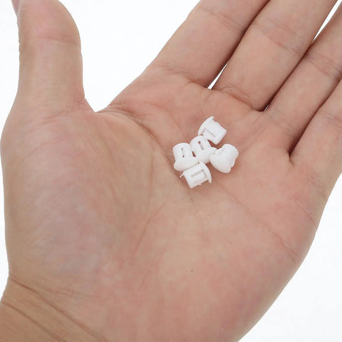 Close-up of hand holding small white plastic hole plugs from 100 pcs set for cabinets shelves and office spaces no mess easy install