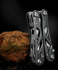 Everyday Carry 15 In 1 EDC Multitool Pliers with Spring Assisted Pliers and Safety Lock, hollow skeleton design against rock
