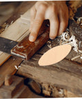 Person using a hand saw on wood with a beech wood joiner biscuit for projects. 100 Pack Hella Strong Beech Wood Joiner Biscuits For Heavy Duty Woodworking And Furniture Assembly Oval Slotting Dowels To Whip Up Sweet DIY Craft Projects Fast.