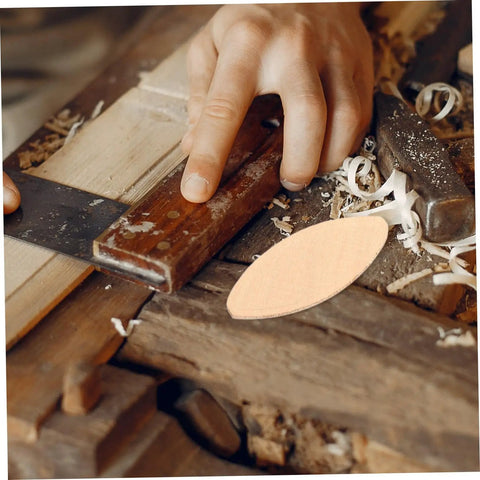 Person using a hand saw on wood with a beech wood joiner biscuit for projects. 100 Pack Hella Strong Beech Wood Joiner Biscuits For Heavy Duty Woodworking And Furniture Assembly Oval Slotting Dowels To Whip Up Sweet DIY Craft Projects Fast.