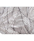 Close-up of white fabric with black intricate pattern design, showcasing detailed stitching and texture.
