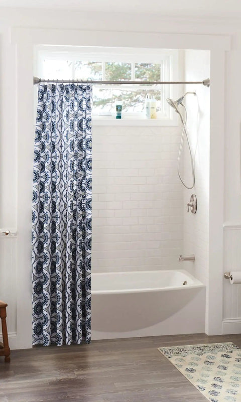 Modern bathroom with blue patterned shower curtain in white tiled bathtub and brushed nickel accessories.