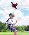 Child riding Backyard Zip Line Kit For Kids And Adults, 120 Foot Outdoor Zipline With Swing Seat, Spring Brake, Safety Harness