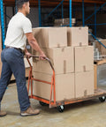 Person pushing a cart with boxes, fitted with heavy duty 6 inch rubber on cast iron caster wheels for smooth rolling and shock absorption.
