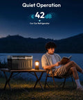22Qt Portable Car Fridge And Freezer With Dual 12V Dc And 110V Ac Plugs on a table beside a man reading at night.