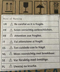Warning label for fragile items, providing multiple language instructions for handling and care.