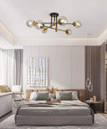 Lit Modern Glass Globe Sputnik Chandelier Flush Mount Ceiling Light In Black And Gold Finish in a modern bedroom setting.