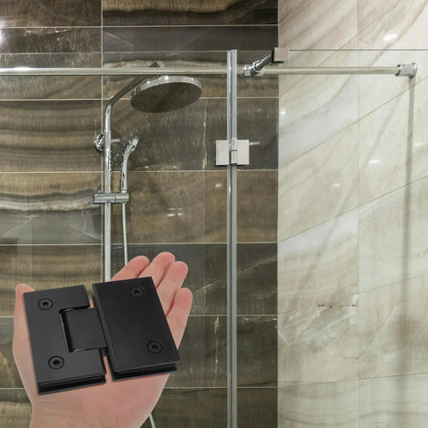 Matte black 304 stainless steel shower door hinge held in hand, bathroom background, for frameless doors, 180-degree clamp